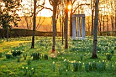 MORTON HALL GARDENS, WORCESTERSHIRE: THE MONOPTEROS, PARKLAND MEADOW, DAFFODILS, NARCISSUS, COLONNADE, PARK, SUNRISE, SPRING