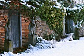 STATUARY IN THE SNOW AND OLD WOODEN DOOR IN WALL AT SPRIVERS GARDEN  SUSSEX