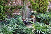 PASHLEY MANOR GARDEN, EAST SUSSEX. SPRING - THE WALLED KITCHEN GARDEN - CARDOONS WITH METAL SEAT AND TERRACOTTA CONTAINERS WITH TULIPA CHINA TOWN. BENCH, APRIL, VEGETABLE