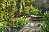 MORTON HALL, WORCESTERSHIRE: SPRING, APRIL, PATH WITH TULIPS, WATER FOUNTAIN, ARCH WITH CLEMATIS. CLASSIC, FORMAL, ENGLISH, COUNTRY, GARDEN