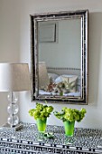 BUTTER WAKEFIELD HOUSE, LONDON: ZOES BEDROOM: MOTHER OF PEARL INLAY CHEST OF DRAWERS WITH ANTIQUE BLACK & WHITE MIRROR AND GLASS LAMP. GREEN GLASS CONTAINERS WITH VIBURNUM
