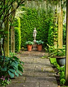 COTTAGE ROW, DORSET: PATH, WOODEN PERGOLA, HOSTAS IN CONTAINERS, STATUE. FORMAL, ENGLISH, CLASSIC, GARDEN, FRAME, FRAMED, VIEW