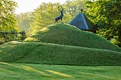 HAZELBY HOUSE, BERKSHIRE: GRASS TURF MOUND WITH STAG STATUE, SCULPTURE ON TOP, SUMMER, LAWN