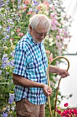 ROGER PARSONS SWEET PEAS, WEST SUSSEX: ROGER PARSONS WATERING SWEET PEAS IN THE POLYTUNNEL