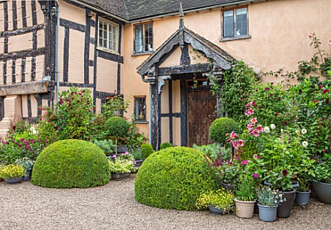 WOLLERTON_OLD_HALL_SHROPSHIRE_PINK_PAINTED_HOUSE_HALL_FRONT_GRAVEL_DRIVE_CONTAINERS_LILIES_CLIPPED_T