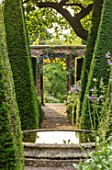 WOLLERTON OLD HALL, SHROPSHIRE: WELL GARDEN WITH VIEW THROUGH CLIPPED YEWS TOWARD THE CROFT GARDEN. TOPIARY. WATER FEATURE , PATH, VISTA, GRAVEL, POND, CIRCULAR