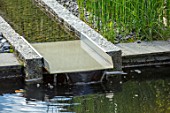 PRIVATE GARDEN, SURREY: DESIGNER ANTHONY PAUL: GRANITE RILL, POND, POOL, WATER, PEBBLES, FEATURE, REEDS, EQUISETUM, HYEMALE, HORSETAIL, SPOUT, CANAL, WATERFALL