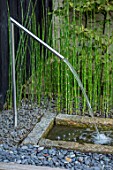 PRIVATE GARDEN, SURREY: DESIGNER ANTHONY PAUL: METAL WATER SPOUT, GRANITE RILL, EQUISETUM HYEMALE, HORSETAIL, PEBBLES, WATER FEATURE, FOUNTAIN, JET