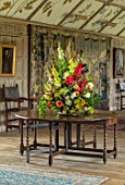 PARHAM, SUSSEX: THE LONG GALLERY - CONTAINER FLOWER DISPLAY WITH GLADIOLUS. DAHLIAS, ZINNIAS, FOLAIGE OF BEECH, OAK, COTINUS. DISPLAY, CUTTING, ARRANGEMENT