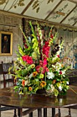 PARHAM, SUSSEX: THE LONG GALLERY - CONTAINER FLOWER DISPLAY WITH GLADIOLUS. DAHLIAS, ZINNIAS, FOLAIGE OF BEECH, OAK, COTINUS. DISPLAY, CUTTING, ARRANGEMENT