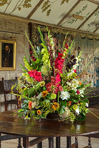 PARHAM_SUSSEX_THE_LONG_GALLERY__CONTAINER_FLOWER_DISPLAY_WITH_GLADIOLUS_DAHLIAS_ZINNIAS_FOLAIGE_OF_B