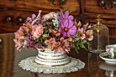 PARHAM, SUSSEX: GREEN ROOM - WHITE AND GOLD CONTAINER WITH PINK ALSTROEMERIA, COSMOS, RHAMNUS, WHITE SALVIA, JOE PYE WEED, PEACH COLOURED ASTER