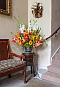 PARHAM, SUSSEX: ENTRANCE HALL - CONTAINER WITH SUNFLOWERS, RED ALSTROEMERIA, GLADIOLUS AND BRONZE FENNEL