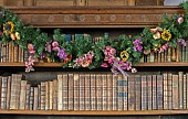 BADDESLEY CLINTON, WARWICKSHIRE: THE NATIONAL TRUST- CHRISTMAS, 15TH AND 16TH CENTURY MOATED MANOR HOUSE. THE LIBRARY, OAK BOOKSHELVES, DRIED FLOWER GARLANDS