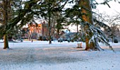 MORTON HALL, WORCESTERSHIRE: WINTER - VIEW OF HOUSE FROM PARKLAND, BENCH, SEATING, SEAT, CEDAR, FROST, SNOW, COLD, DECEMBER, ENGLISH, COUNTRY, GARDEN