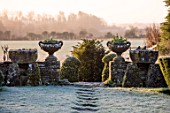 RODMARTON MANOR, GLOUCESTERSHIRE, WINTER. FEBRUARY - FROST, PATH THROUGH THE TROUGHERY. STONE URNS, CONTAINERS, DAWN LIGHT, SUNRISE, THE MANOR, ENGLISH, COUNTRY, GARDEN