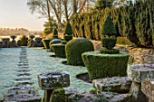 RODMARTON MANOR, GLOUCESTERSHIRE, WINTER. FEBRUARY - FROST, PATH, TROUGHERY. STONE URNS, CONTAINERS, DAWN LIGHT, SUNRISE, THE MANOR, ENGLISH, COUNTRY, GARDEN, CLIPPED YEW TOPIARY