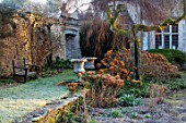 RODMARTON MANOR, GLOUCESTERSHIRE, WINTER - WOODEN BENCH, SEAT, HYDRANGEAS AND STONE URNS IN LEISURE GARDEN WITH MANOR BEHIND. ENGLISH, COUNTRY, GARDEN, FEBRUARY
