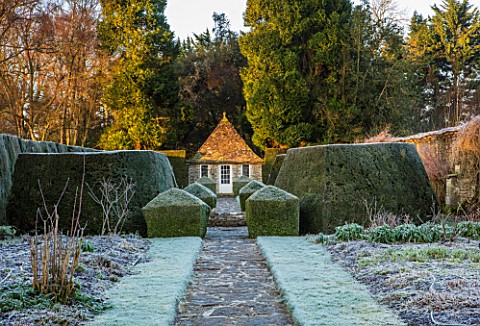 RODMARTON_MANOR_GLOUCESTERSHIRE_WINTER__PATH_WITH_STONE_SUMMERHOUSE_AND_YEW_TOPIARY_HEDGES_IN_FROST_