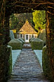 RODMARTON MANOR, GLOUCESTERSHIRE, WINTER - PATH WITH STONE SUMMERHOUSE AND YEW TOPIARY HEDGES IN FROST. ENGLISH, COUNTRY, GARDEN, FEBRUARY, HEDGING, FORMAL