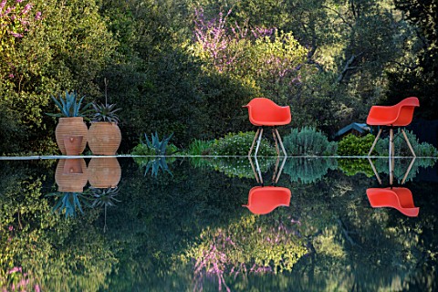 SKOPOS_DESIGN_CORFU_BLACK_INFINITY_POOL_WITH_REFLECTIONS_ORANGE_CHAIRS_TERRACOTTA_CONTAINERS_WITH_AG