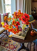 THE OLD PARSONAGE, DORSET: THE SITTING ROOM WITH JUG OF TULIPS PCIKED FROM THE GARDEN. INTERIOR, LIVING ROOM, DISPLAY, DECORATIVE, HOME, COLOURFUL, ORANGE FLOWERS, CUSHIONS.TABLE.