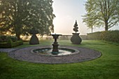 MITTON MANOR, STAFFORDSHIRE: THE MANOR AND FOUNTAIN IN FRONT. FOG, MIST, FOUNTAIN, TOPIARY, CLIPPED, WATER, SPRING, DAWN, SUNRISE, ENGLISH, COUNTRY, GARDEN