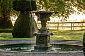 MITTON MANOR, STAFFORDSHIRE: CIRCULAR FOUNTAIN AT FRONT OF MANOR IN SPRING. WATER, TOPIARY, DAWN, SUNRISE, CLIPPED