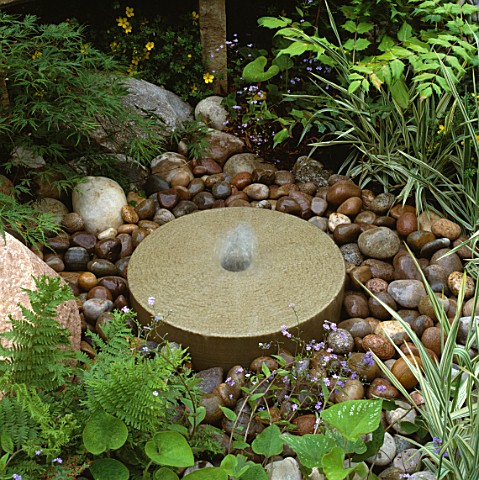 SIMPLE_MILLSTONE_FOUNTAIN_SURROUNDED_BY_PEBBLES_IN_DALES_STONE_COMPANY_GARDEN_CHELSEA_1994