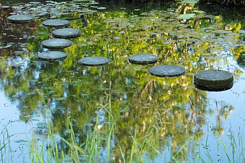 CHILWORTH_MANOR_SURREY_STEPPING_STONE_PATH_OVER_WATER_IN_RIGINAL_MONASTIC_STEWPOND_REFLECTIONS