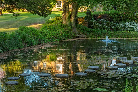 CHILWORTH_MANOR_SURREY_STEPPING_STONES_OVER_ORIGINAL_MONASTIC_STEWPOND_WITH_FOUNTAIN_AND_HOUSE_REFLE