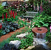 MILLSTONE WATERFALL IN COTTAGE GARDEN SETTING WITH SEAT IN B/G. DAILY MIRROR GARDEN. CHELSEA 1994