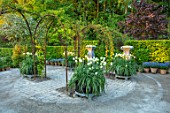 CLAUS DALBY GARDEN, DENMARK: GARDEN ROOM, GRAVEL, ARCHES, HALF BARREL CONTAINERS PLANTED WITH WHITE AND GREEN SPRING GREEN