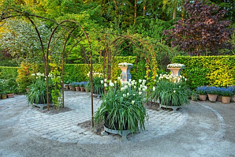 CLAUS_DALBY_GARDEN_DENMARK_GARDEN_ROOM_GRAVEL_ARCHES_HALF_BARREL_CONTAINERS_PLANTED_WITH_WHITE_AND_G