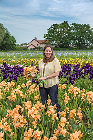 HOWARDS_NURSERIES_NORFOLK_CHRISTINE_HOWARD_WITH_IRISES_IRIS_BEDS_FIELDS__WITH_HOUSE_IN_BACKGROUND_CO