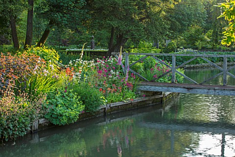ABLINGTON_MANOR_GLOUCESTERSHIRE_VIEW_ACROSS_COLN_RIVER_TO_ISLAND_BED_AND_WOODEN_FOOTBRIDGE_REFLECTIO