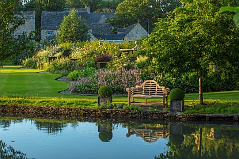 ABLINGTON_MANOR_GLOUCESTERSHIRE_VIEW_ACROSS_RIVER_COLN_TO_HMANOR_HOUSE__WOODEN_BENCH_SEAT_LAWN_SUMME