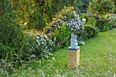 ASTHALL MANOR, OXFORDSHIRE: LAWN WITH ROSES HEDGE AND MEADOW BEYOND. SCULPTURE SOGNO DALTEZZA BY ROB GOOD. ENGLISH, COUNTRY, GARDENS