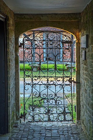 THE_WALLED_GARDEN_AT_COWDRAY_WEST_SUSSEX_VIEW_OUT_OF_ORNATE_METAL_ENTRANCE_GATE_TO_GARDENS_ENGLISH_C