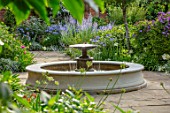 MORTON HALL, WORCESTERSHIRE: SOUTH GARDEN, SUMMER. CIRCULAR FOUNTAIN, WALL, PEROVSKIA, ROSES, PATHS, EVENING LIGHT, FORMAL, COUNTRY, GARDEN, ENGLISH, CLASSIC, WATER, FEATURE
