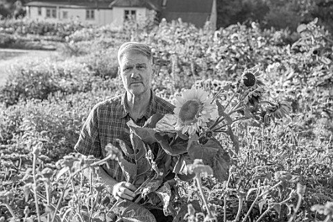 ASTON_POTTERY_OXFORDSHIRE_BLACK_AND_WHITE_PHOTOGRAPH_OF_STEPHEN_BAUGHAN_HOLDING_SUNFLOWERS_IN_THE_AN