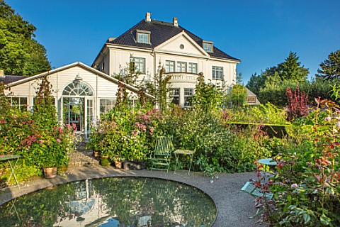 CLAUS_DALBY_GARDEN_DENMARK_THE_HOUSE_SEEN_FROM_THE_GARDEN_WITH_CIRCULAR_POND_POOL_AND_GRENHOUSE_SUMM