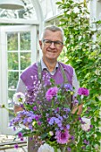 CLAUS DALBY GARDEN, DENMARK: CLAUS DALBY IN HIS GREENHOUSE HOLDING A BOUQUET OF FLOWERS FROM THE GARDEN