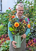 CLAUS DALBY GARDEN, DENMARK: CLAUS DALBY IN HIS GARDEN HOLDING A BOUQUET OF ORANGE FLOWERS IN HIS GARDEN