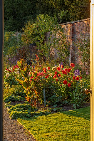 KELMARSH_HALL_NORTHAMPTONSHIRE_VIEW_THROUGH_GATE_TO_BORDER_BESIDE_WALL_WITH_CANNAS_AND_ORANGE_PALE_R
