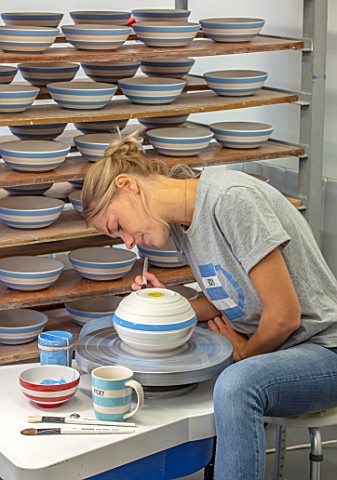 ALHAM_FARM_SOMERSET_CORNISHWARE_THE_POTTERY__VICKY_APPLYING_ICONIC_BLUE_STRIPE_BY_HAND_TO_FIRED_BOWL