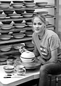 ALHAM FARM, SOMERSET: CORNISHWARE: THE POTTERY - VICKY APPLYING ICONIC BLUE STRIPE BY HAND TO FIRED BOWLS, BLACK AND WHITE