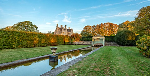 RADCOT_HOUSE_OXFORDSHIRE_THE_HOUSE_SEEN_FROM_THE_LONG_POND_BEECH_HEDGES_HEDGING_POOL_CANAL_GAZEBO_SE