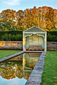 RADCOT HOUSE, OXFORDSHIRE: THE LONG POND. BEECH HEDGES, HEDGING, POOL, CANAL, GAZEBO, SEAT, SEATING, AUTUMN, REFLECTIONS, REFLECTED