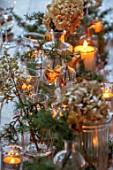 GIBBONS CROFT, WEST CLANDON, SURREY: CHRISTMAS. OPEN PLAN KITCHEN, DINING ROOM. TABLE DECORATIONS. GLASSWARE, CANDLES, PINE, DRIED HYDRANGEAS, ROSES